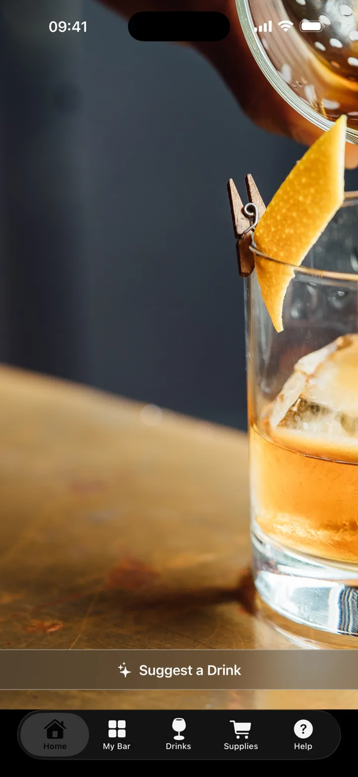 The bartender.live home screen: an old fashioned being strained into a rocks glass on a brass bar top, with a Suggest a Drink button and tabs for Home, My Bar, Drinks, Supplies, and Help